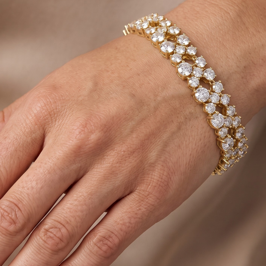 A close-up of a gold bracelet with multiple rows of sparkling clear moissanite gemstones worn on a person's wrist.