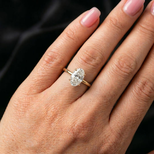 Close-up of a hand wearing a moissanite diamond ring on a dark background