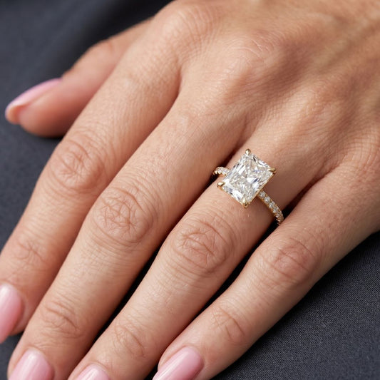 Rose gold moissanite diamond ring on a hand against a dark background