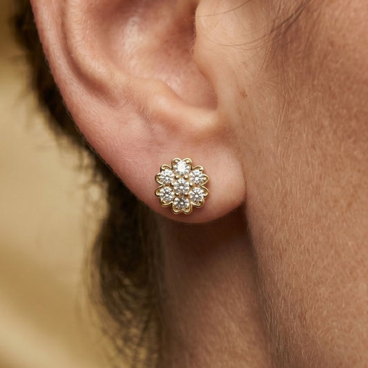 Close-up of a gold and moissanite diamond earring on an ear.