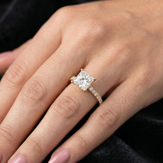 Rose gold ring with a large moissanite diamond on a hand against a dark background