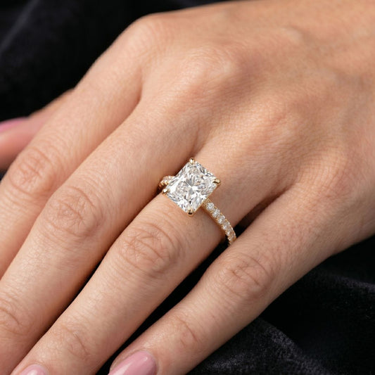 Close-up of a hand wearing a moissanite diamond ring with a black background