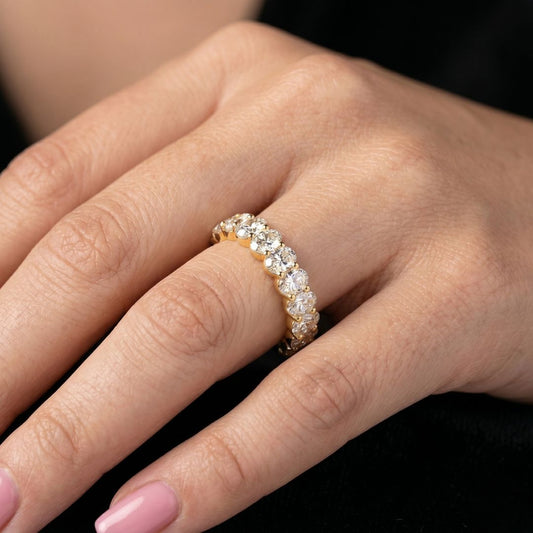 Close-up of a hand wearing a moissanite diamond ring on a dark background