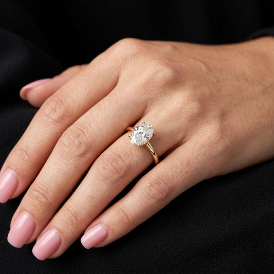 Hand wearing a gold ring with a moissanite diamond on a black background