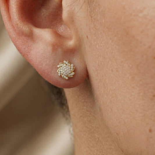 Close-up of a person wearing a gold floral moissanite diamond earring.