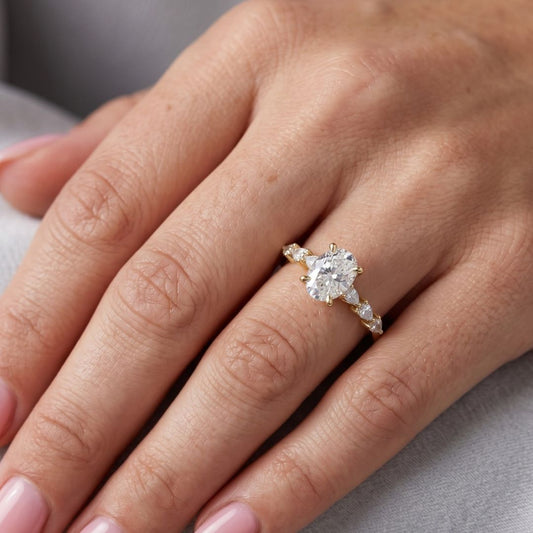 Close-up of a hand wearing a moissanite diamond ring on a neutral background
