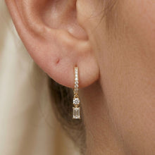 Load image into Gallery viewer, Gold hoop earring with clear moissanite gemstones worn by a person.