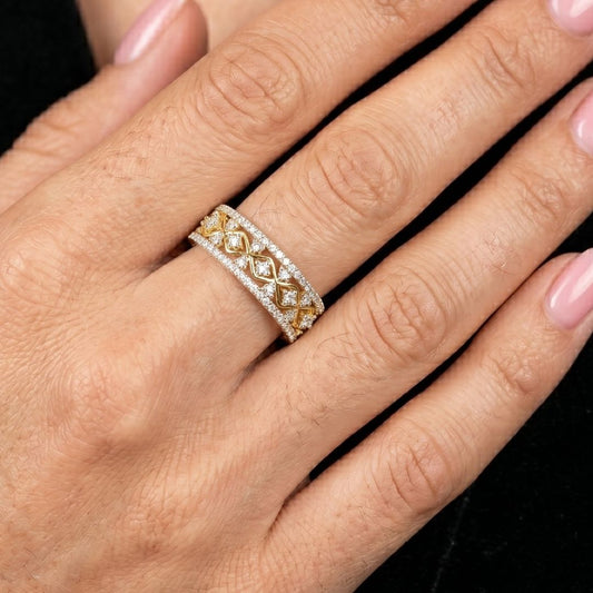 Gold and moissanite diamond ring on a hand against a black background