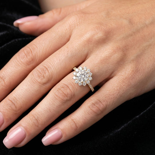 Close-up of a hand wearing a moissanite diamond ring on a black background