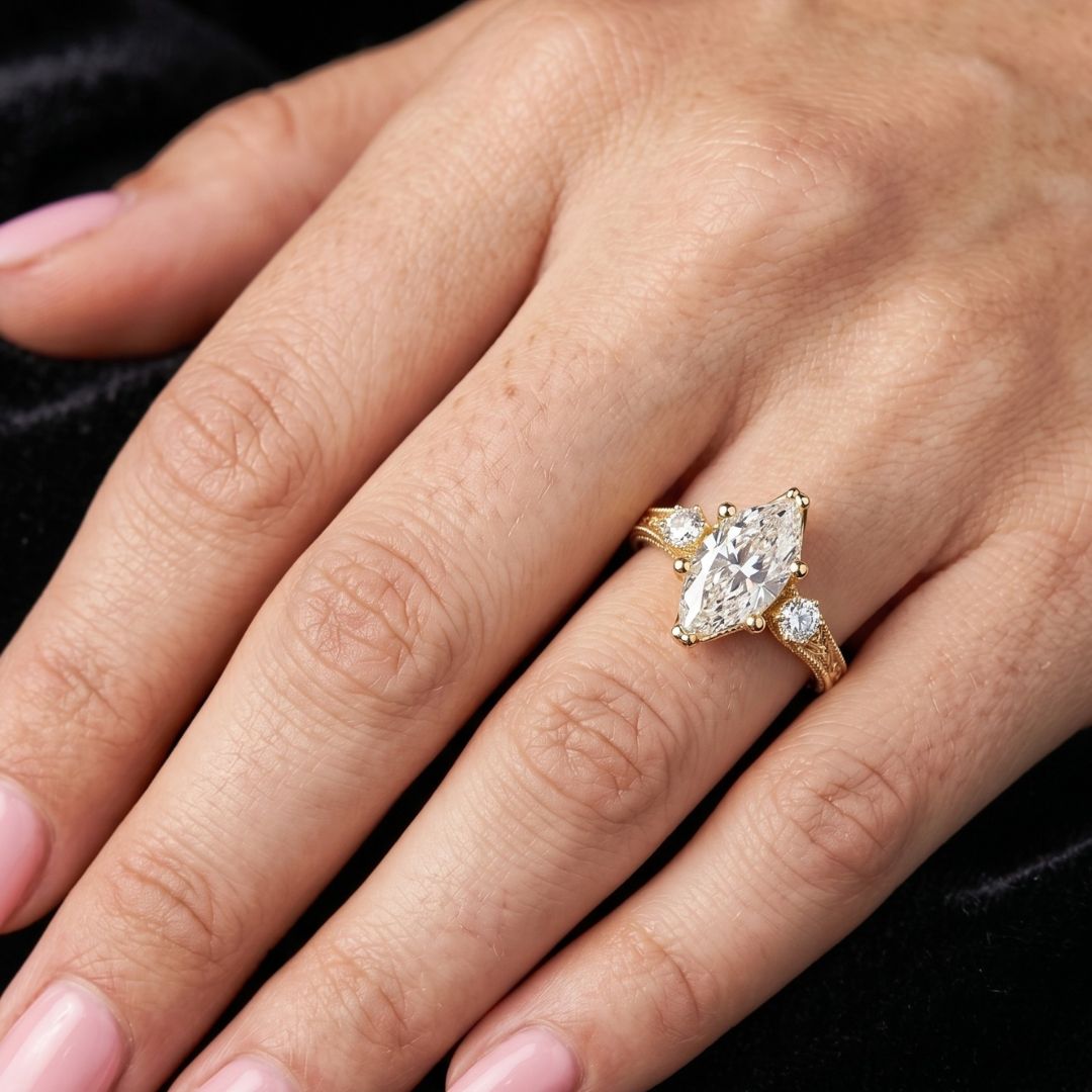 Gold ring with a moissanite diamond on a person's finger against a black background