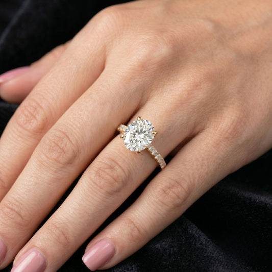 Close-up of a hand wearing a moissanite diamond ring with a dark background