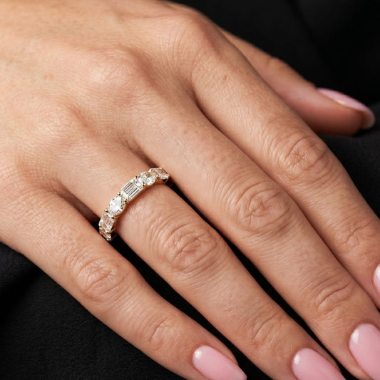 Close-up of a hand wearing a moissanite diamond ring with a black background