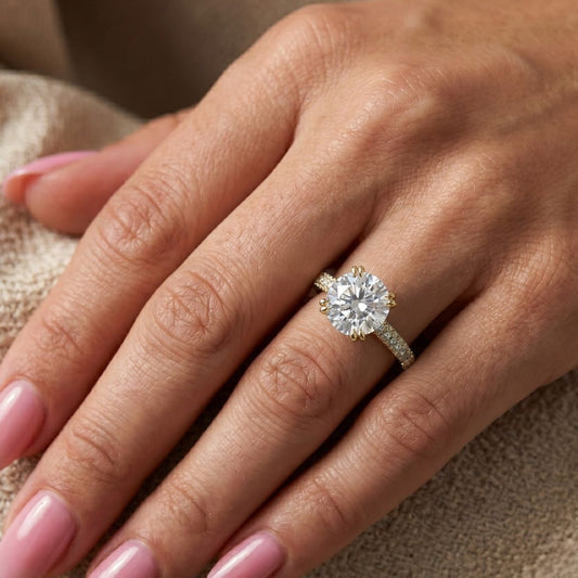 Close-up of a hand wearing a moissanite diamond ring on a neutral background