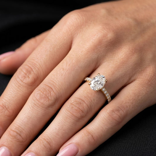 Close-up of a hand wearing a moissanite diamond ring on a dark background