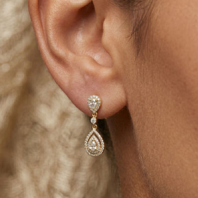 Close-up of a woman's ear wearing a moissanite diamond earring with a blurred background