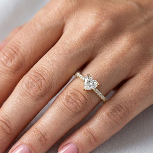 Heart-shaped moissanite diamond ring on a hand against a neutral background