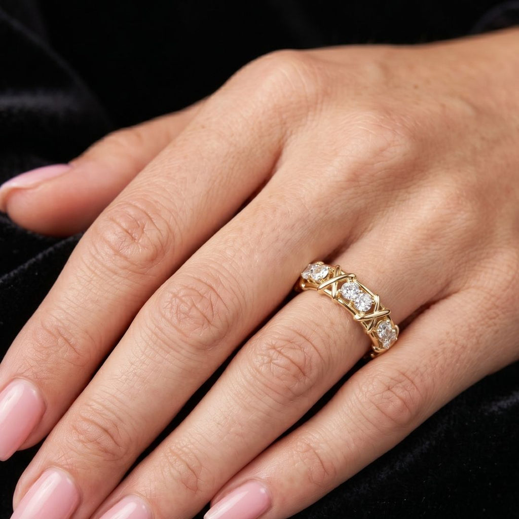 Close-up of a hand wearing a gold ring with moissanite diamonds on a black background