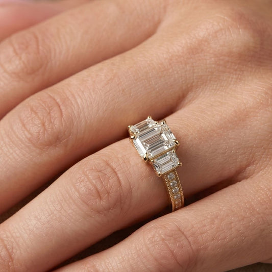 Rose gold ring with emerald-cut moissanite diamonds on a hand
