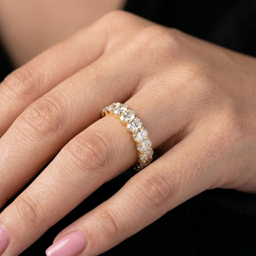 Close-up of a hand wearing a moissanite diamond ring on a dark background