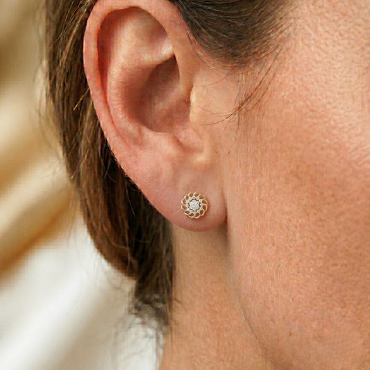 Close-up of an ear wearing a Moissanite Diamond gold earring with a diamond.