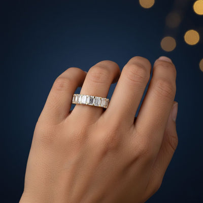 Hand wearing a Moissanite diamond ring with a dark blue background
