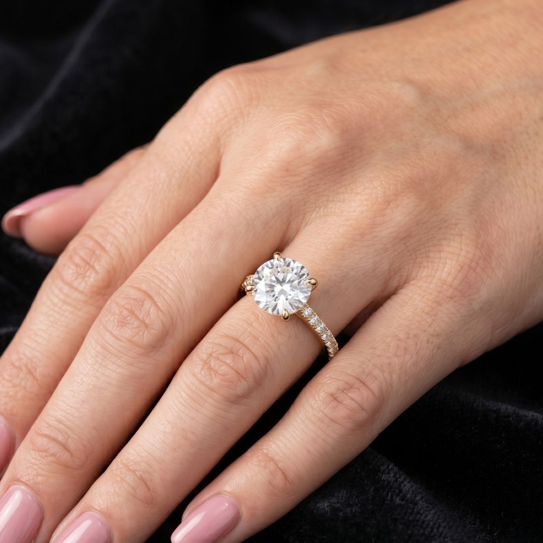Close-up of a hand wearing a moissanite diamond ring on a dark background