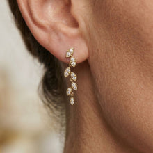 Load image into Gallery viewer, Gold earrings with clear Moissanite stones worn by a person, close-up on ear.