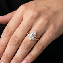Load image into Gallery viewer, Gold ring with a pear-shaped moissanite diamond on a hand against a black background