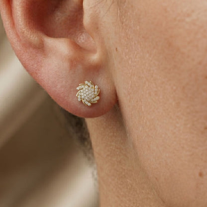 Close-up of a person wearing a gold floral moissanite diamond earring.