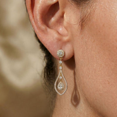Close-up of a woman's ear wearing a moissanite diamond earring with a blurred background