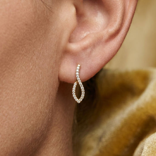 Close-up of an ear wearing a moissanite diamond earring with a blurred background