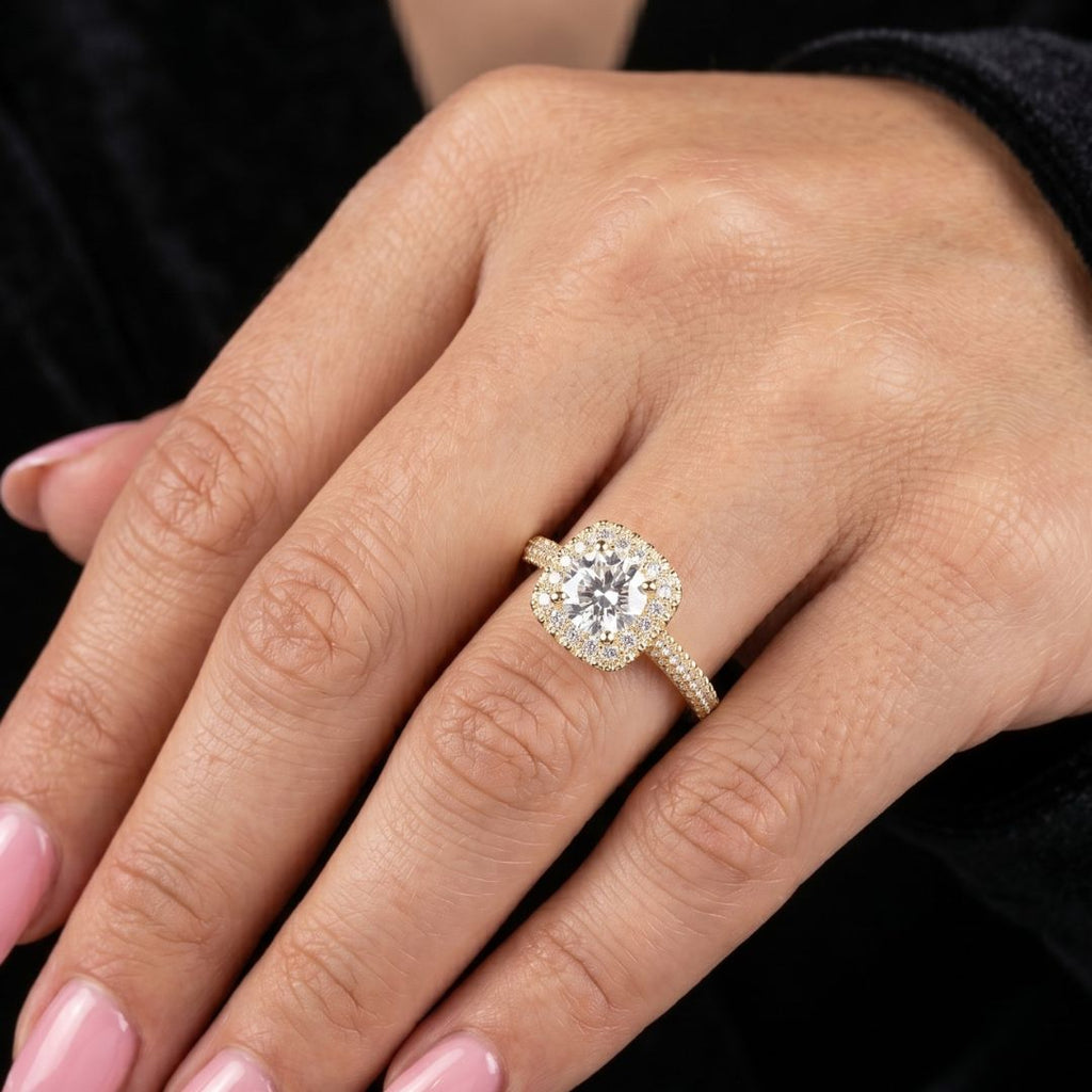 Close-up of a hand wearing a moissanite diamond ring with a black background