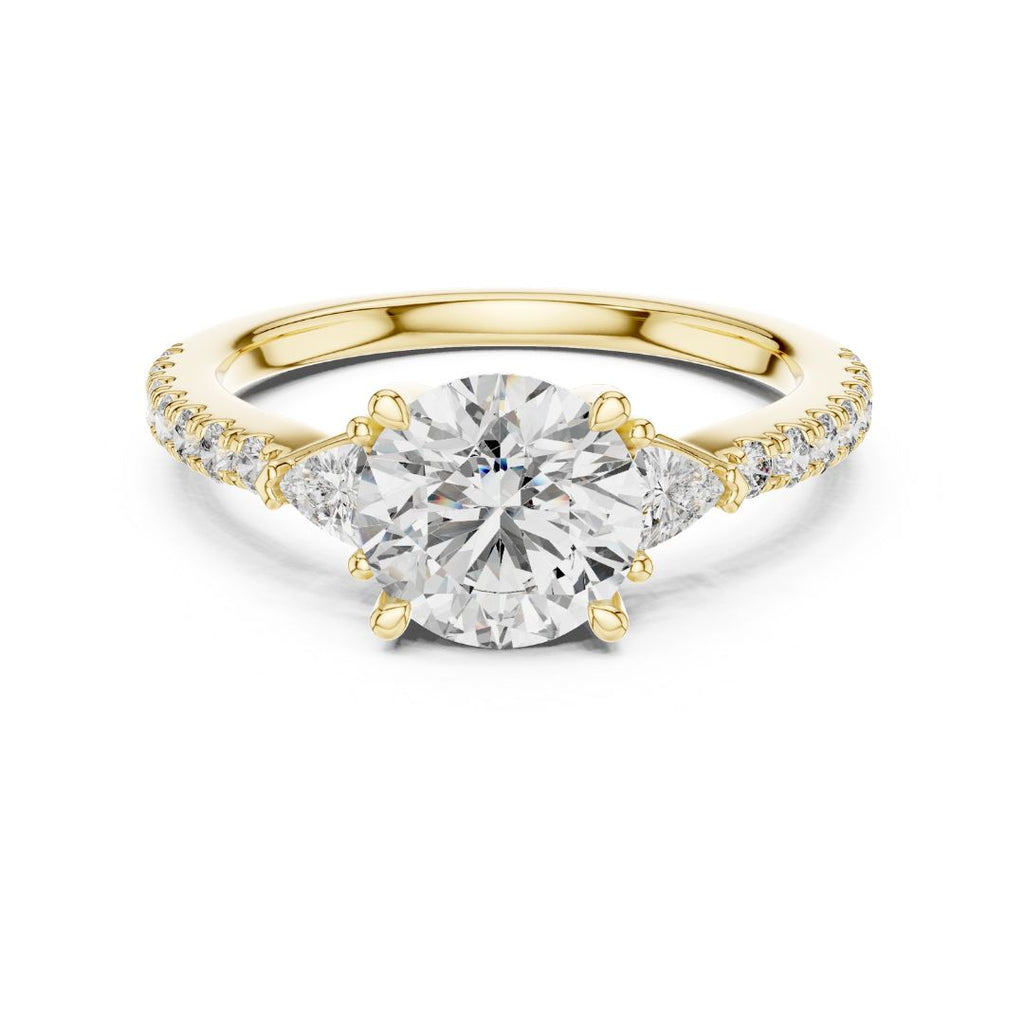 Gold ring with a large moissanite diamond and smaller diamonds on the band against a white background
