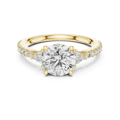 Gold ring with a large moissanite diamond and smaller diamonds on the band against a white background
