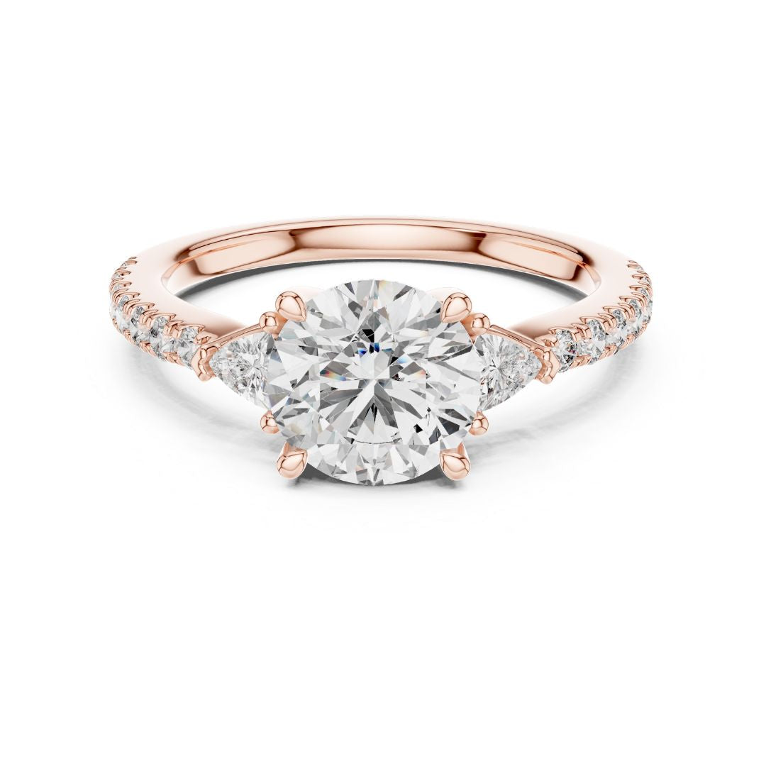 Rose gold ring with a large moissanite diamond and smaller diamonds on the band against a white background