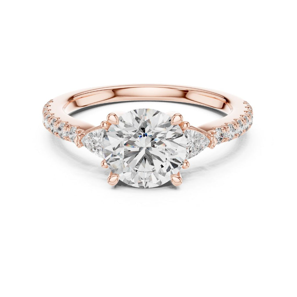 Rose gold ring with a large moissanite diamond and smaller diamonds on the band against a white background