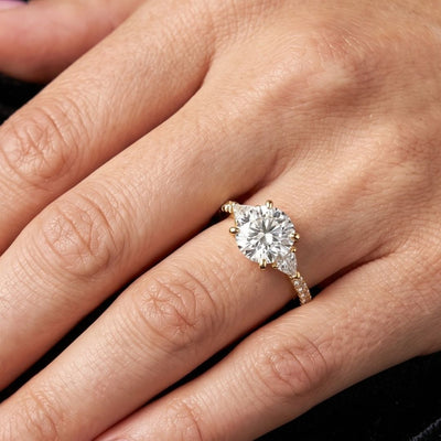 gold ring with a large moissanite diamond on a hand