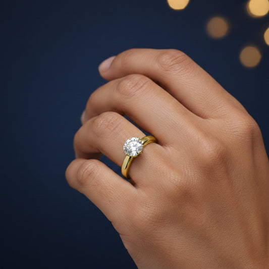Gold ring with a 1ct moissanite diamond on a hand against a dark background