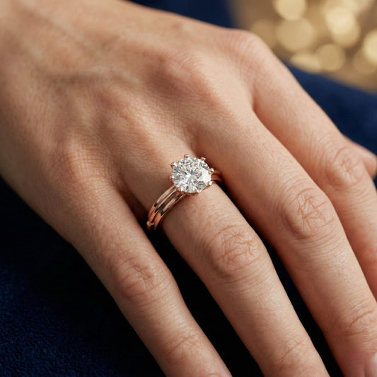 Rose gold ring with a 1ct moissanite  diamond on a hand against a blurred background