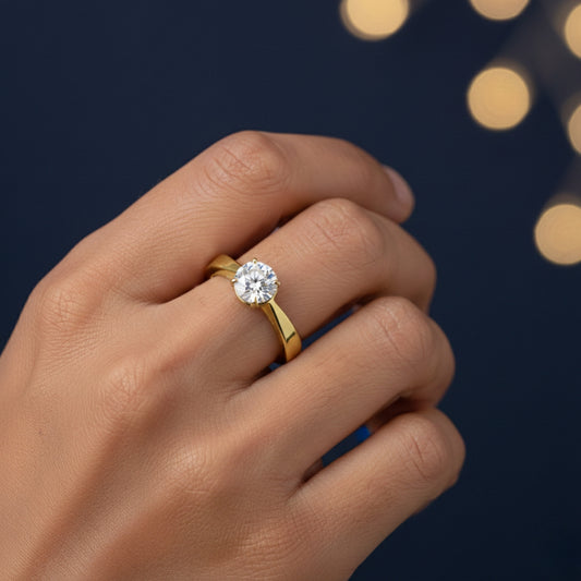 Gold ring with a diamond on a 1ct moissanite diamond ring in hand against a dark background with bokeh lights